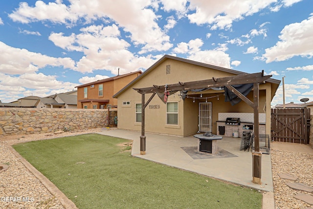 back of property featuring stucco siding, a pergola, a patio area, a gate, and an outdoor kitchen