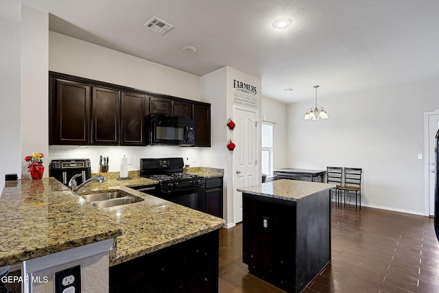 kitchen with black appliances, a sink, light stone countertops, a center island, and pendant lighting