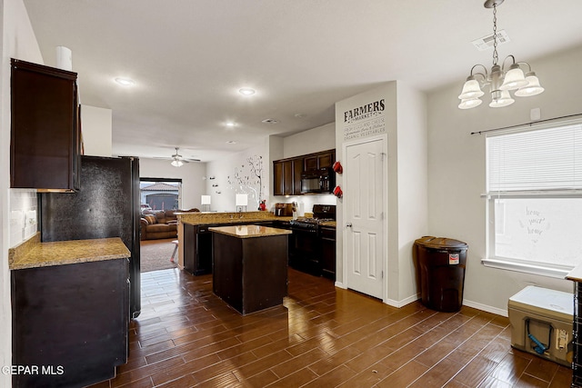 kitchen with black appliances, ceiling fan, a center island, dark brown cabinetry, and a chandelier