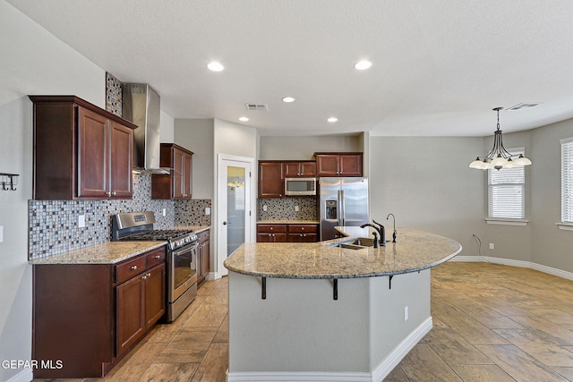 737 Colonial Blf, El Paso, TX 79928 - kitchen featuring stainless steel appliances, wall chimney range hood, backsplash, a breakfast bar, and light stone countertops