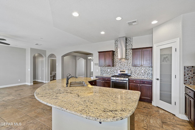 737 Colonial Blf, El Paso, TX 79928 - kitchen featuring stainless steel gas range, a sink, wall chimney range hood, arched walkways, and backsplash