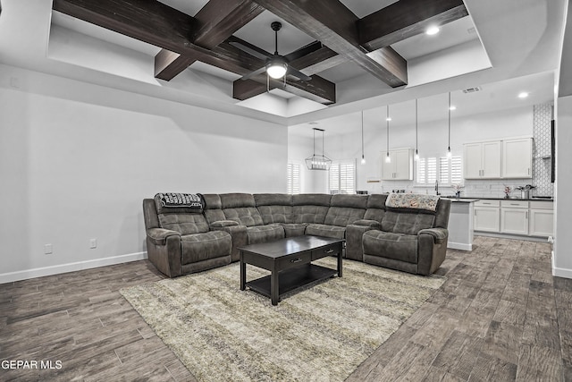 living room with coffered ceiling, a ceiling fan, wood finished floors, baseboards, and beamed ceiling