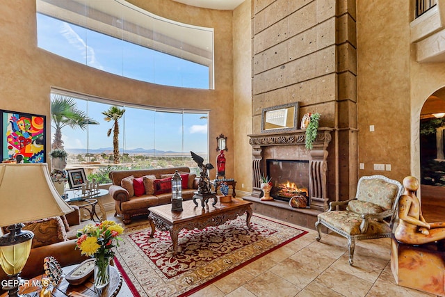 6664 Tuscany Ridge Dr, El Paso, TX 79912 - living area featuring a high ceiling, a lit fireplace, healthy amount of natural light, and arched walkways