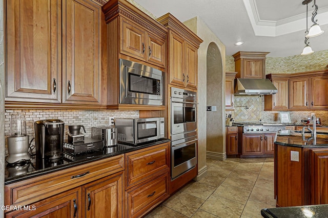 6664 Tuscany Ridge Dr, El Paso, TX 79912 - kitchen featuring stainless steel appliances, extractor fan, tasteful backsplash, brown cabinetry, and ornamental molding