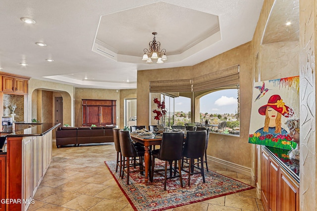 6664 Tuscany Ridge Dr, El Paso, TX 79912 - dining room with a tray ceiling, arched walkways, a chandelier, light stone finish floors, and recessed lighting