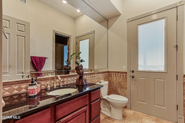 6664 Tuscany Ridge Dr, El Paso, TX 79912 - bathroom featuring tile walls, vanity, toilet, a wainscoted wall, and recessed lighting