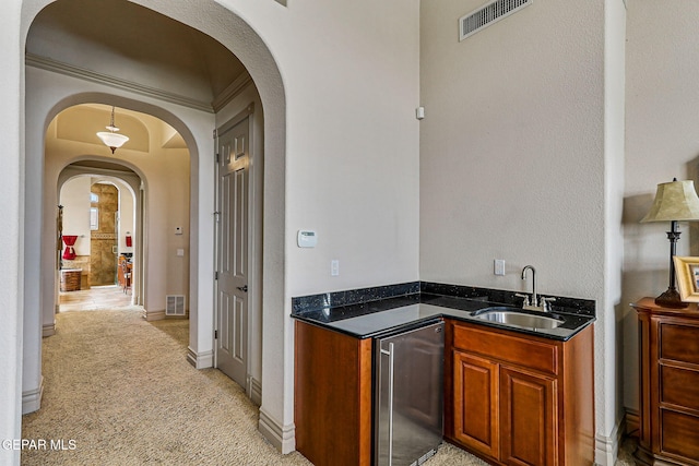 6664 Tuscany Ridge Dr, El Paso, TX 79912 - bar with a sink, fridge, arched walkways, and light colored carpet