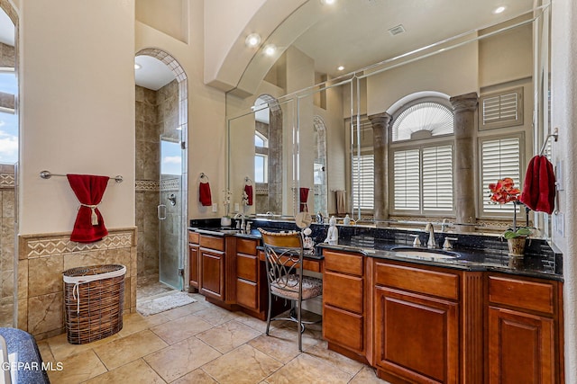 6664 Tuscany Ridge Dr, El Paso, TX 79912 - bathroom featuring tile walls, a shower stall, double vanity, and wainscoting