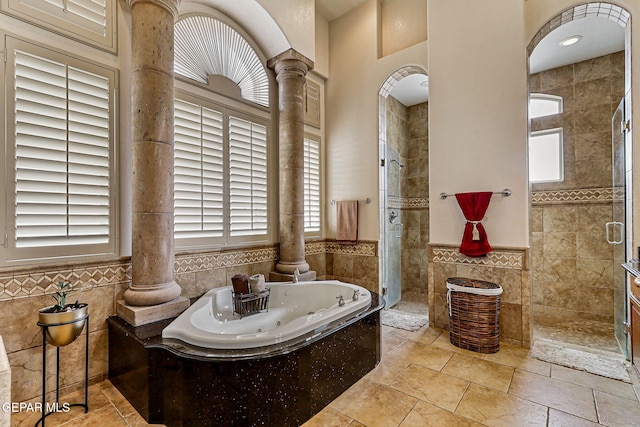 6664 Tuscany Ridge Dr, El Paso, TX 79912 - full bathroom with decorative columns, tile walls, a shower stall, a whirlpool tub, and a wainscoted wall