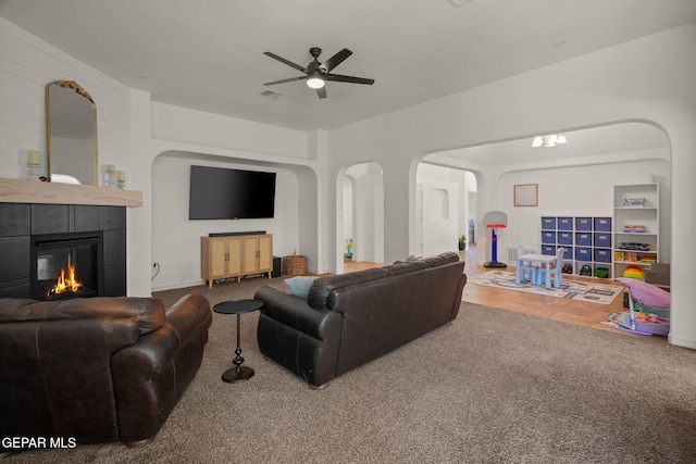 14328 N Cave Dr, El Paso, TX 79938 - carpeted living room featuring arched walkways, ceiling fan, and a tiled fireplace