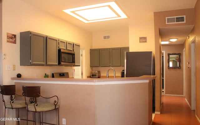 2445 Nancy Mcdonald Dr, El Paso, TX 79936 - kitchen featuring stainless steel appliances, a kitchen breakfast bar, a peninsula, light countertops, and tile patterned flooring