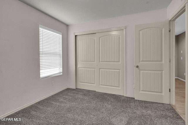 unfurnished bedroom with a closet, carpet floors, and baseboards