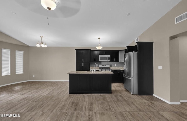 kitchen featuring appliances with stainless steel finishes, dark cabinetry, decorative backsplash, baseboards, and lofted ceiling