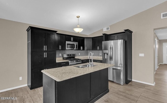 kitchen with stainless steel appliances, dark cabinetry, a sink, tasteful backsplash, and baseboards
