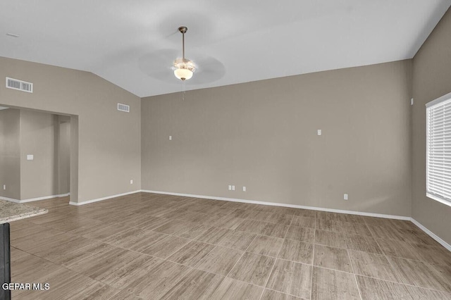 empty room featuring ceiling fan, lofted ceiling, and baseboards