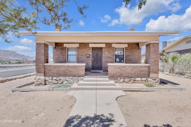 4301 Hueco Ave, El Paso, TX 79903 - view of front of home with a porch, brick siding, fence, a mountain view, and a chimney