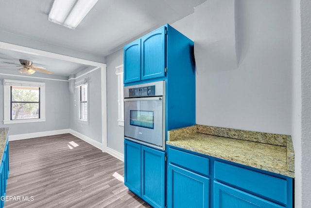4301 Hueco Ave, El Paso, TX 79903 - kitchen featuring stainless steel oven, blue cabinetry, light wood-style floors, a ceiling fan, and baseboards