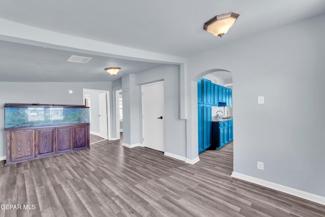 4301 Hueco Ave, El Paso, TX 79903 - unfurnished living room featuring arched walkways, wood finished floors, baseboards, and a sink