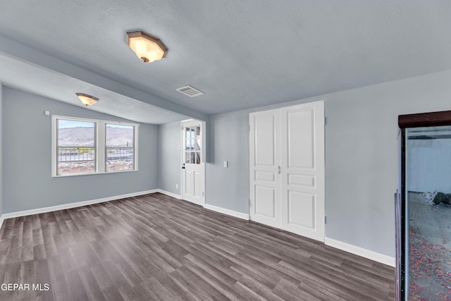 4301 Hueco Ave, El Paso, TX 79903 - unfurnished bedroom with dark wood-style flooring, a textured ceiling, baseboards, and vaulted ceiling