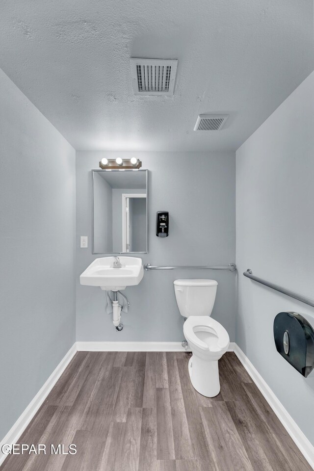 4301 Hueco Ave, El Paso, TX 79903 - half bathroom with toilet, wood finished floors, baseboards, and a textured ceiling