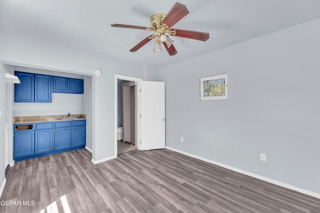 4301 Hueco Ave, El Paso, TX 79903 - unfurnished living room featuring wood finished floors, baseboards, a ceiling fan, and a sink