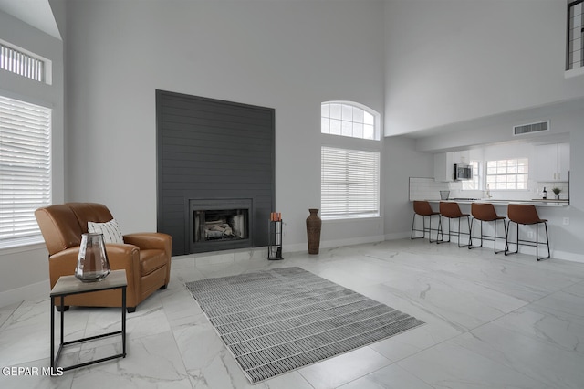 7413 Le Conte Dr, El Paso, TX 79912 - living room featuring light marble finish floors, a towering ceiling, baseboards, and a fireplace