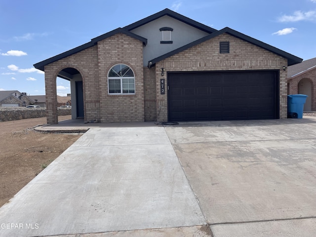 472 Valle Suave Dr, Socorro, TX 79927 - view of front of home featuring brick siding, concrete driveway, a garage, and stucco siding