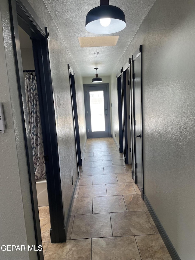472 Valle Suave Dr, Socorro, TX 79927 - corridor featuring a textured wall, a textured ceiling, baseboards, and a barn door