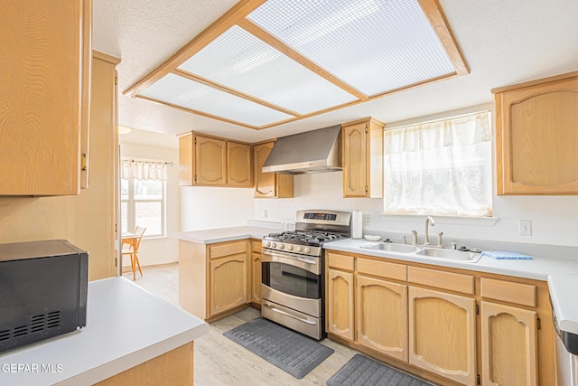 3020 Lake Travis Pl, El Paso, TX 79936 - kitchen with stainless steel gas stove, wall chimney range hood, black microwave, a sink, and light wood-style floors