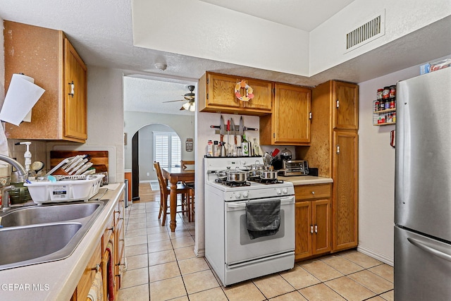 1664 Lou Graham Dr, El Paso, TX 79936 - kitchen featuring freestanding refrigerator, white gas range, a sink, light tile patterned floors, and ceiling fan