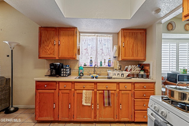 1664 Lou Graham Dr, El Paso, TX 79936 - kitchen with a sink, white range with gas stovetop, decorative backsplash, healthy amount of natural light, and a textured ceiling