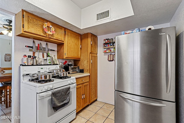 1664 Lou Graham Dr, El Paso, TX 79936 - kitchen featuring freestanding refrigerator, white gas range, light tile patterned floors, light countertops, and ceiling fan