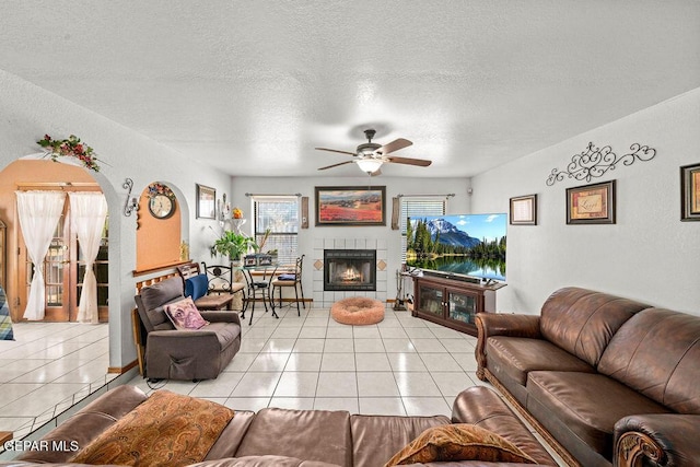 11968 Frances Scobee Dr, El Paso, TX 79936 - living area with a ceiling fan, light tile patterned flooring, a tile fireplace, a textured ceiling, and arched walkways