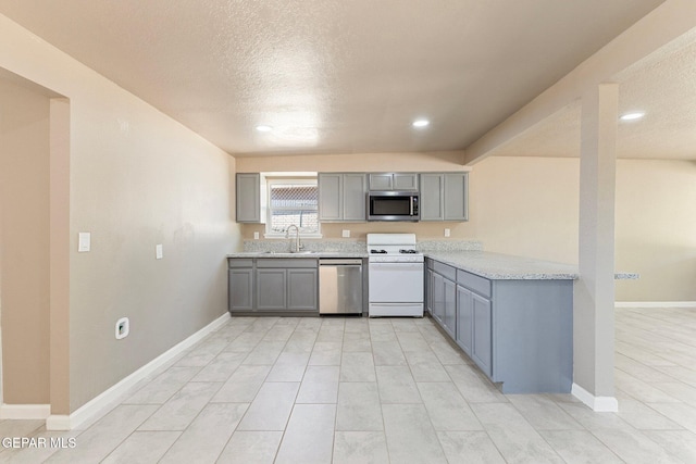 2912 Jarvis Dr, El Paso, TX 79935 - kitchen with appliances with stainless steel finishes, gray cabinetry, a sink, a textured ceiling, and light stone counters