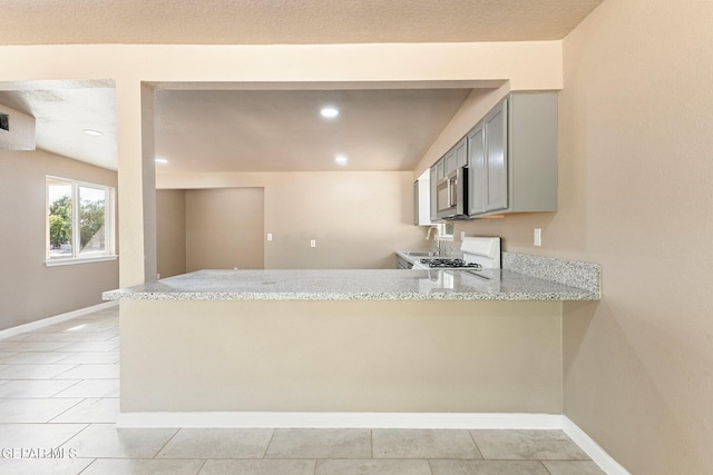 2912 Jarvis Dr, El Paso, TX 79935 - kitchen featuring a peninsula, gas range, stainless steel microwave, gray cabinets, and a sink