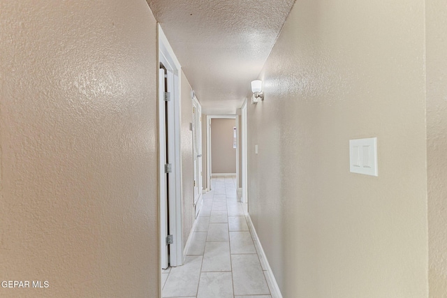 2912 Jarvis Dr, El Paso, TX 79935 - hall with light tile patterned floors, a textured wall, a textured ceiling, and baseboards