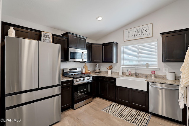 436 Sun Temple Rd, Socorro, TX 79927 - kitchen featuring appliances with stainless steel finishes, a sink, vaulted ceiling, light stone counters, and dark brown cabinets