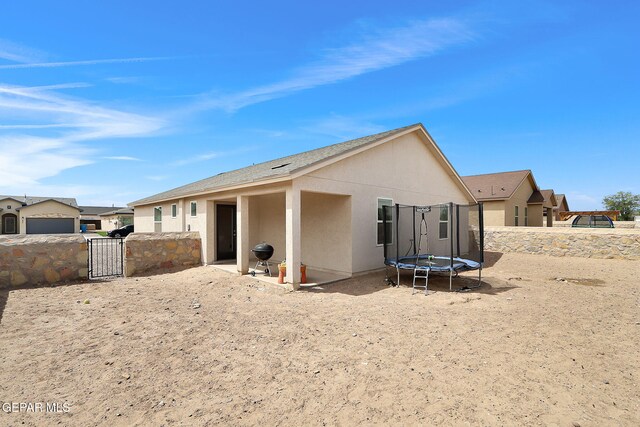 436 Sun Temple Rd, Socorro, TX 79927 - rear view of house featuring a trampoline, a gate, stucco siding, and fence