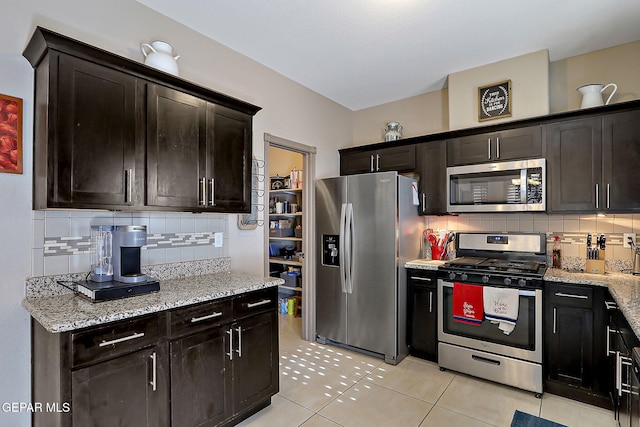 2005 Roy Vinson, El Paso, TX 79938 - kitchen featuring stainless steel appliances, light tile patterned floors, decorative backsplash, light stone counters, and dark brown cabinets