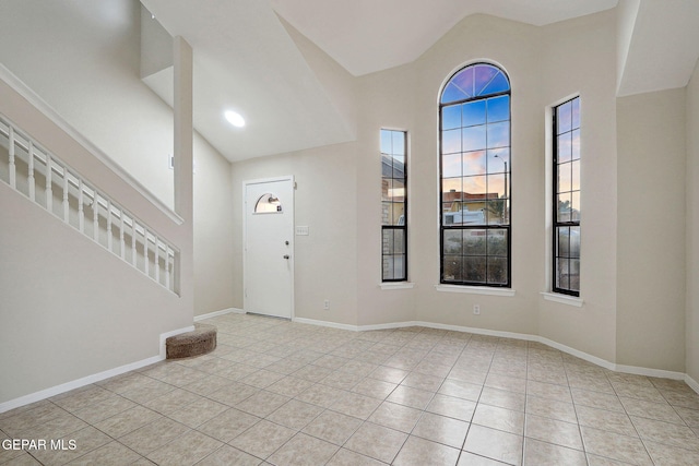 tiled foyer entrance featuring high vaulted ceiling and baseboards