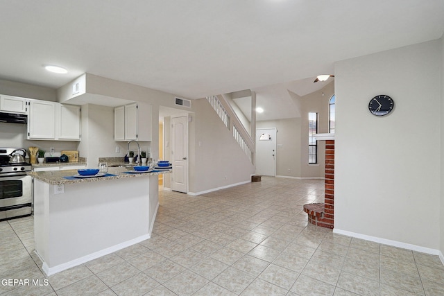 kitchen with stainless steel range with gas stovetop, a sink, light tile patterned flooring, white cabinets, and exhaust hood