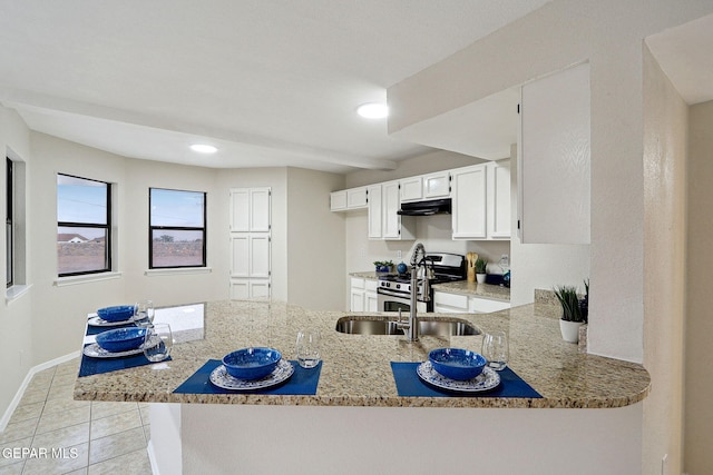 kitchen featuring under cabinet range hood, stainless steel gas range oven, light stone counters, a peninsula, and white cabinets