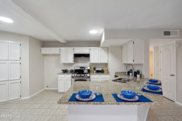 kitchen with stainless steel gas stove, a sink, under cabinet range hood, a peninsula, and white cabinetry