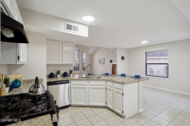 kitchen featuring dishwasher, a sink, a peninsula, light tile patterned flooring, and white cabinets