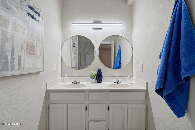 bathroom with a textured wall and double vanity