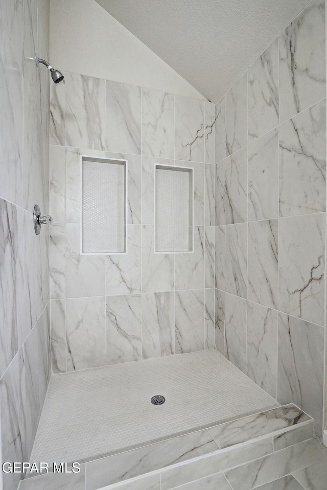 full bath with vaulted ceiling and a tile shower