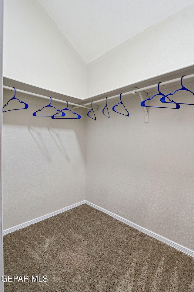 spacious closet featuring dark carpet and lofted ceiling