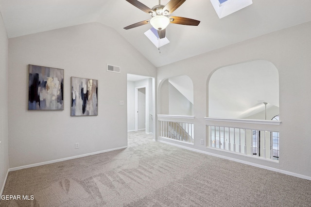 empty room with a skylight, a ceiling fan, carpet, high vaulted ceiling, and baseboards
