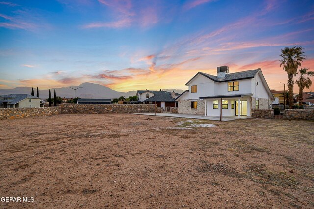 rear view of house with a patio area, stone siding, and a fenced backyard