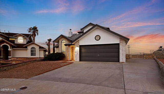 view of front of home with concrete driveway, an attached garage, stucco siding, and brick siding